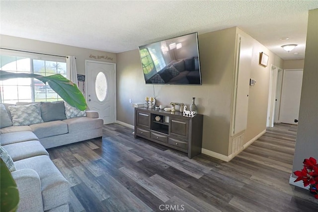 living room featuring baseboards, dark wood-type flooring, and a textured ceiling