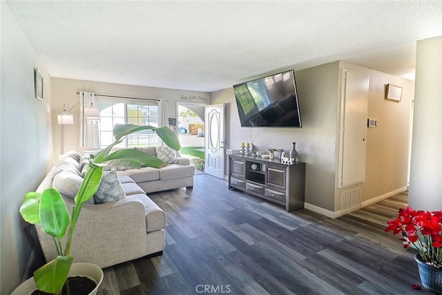 living area featuring dark wood-style floors, visible vents, a textured ceiling, and baseboards