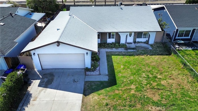 view of front facade with a garage, concrete driveway, a front lawn, and fence