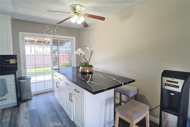 kitchen with dark countertops, a textured ceiling, white cabinetry, and dark wood-style flooring