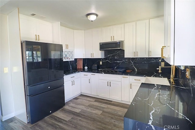 kitchen with white cabinetry, stainless steel microwave, dark wood-style flooring, and freestanding refrigerator