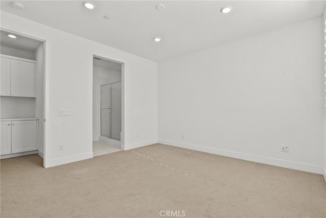 unfurnished bedroom featuring ensuite bath, baseboards, light colored carpet, and recessed lighting