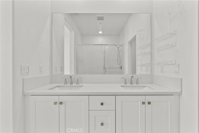 full bath with visible vents, a sink, a shower stall, and double vanity