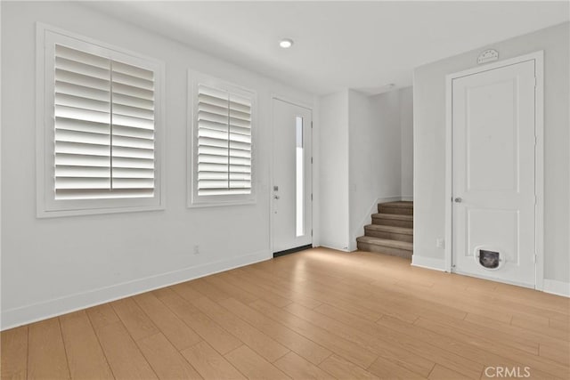 entrance foyer with baseboards, stairs, and light wood-style floors