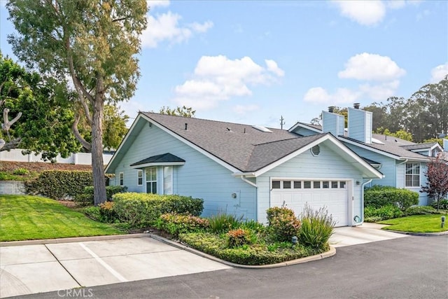 single story home with driveway, a chimney, roof with shingles, an attached garage, and a front lawn