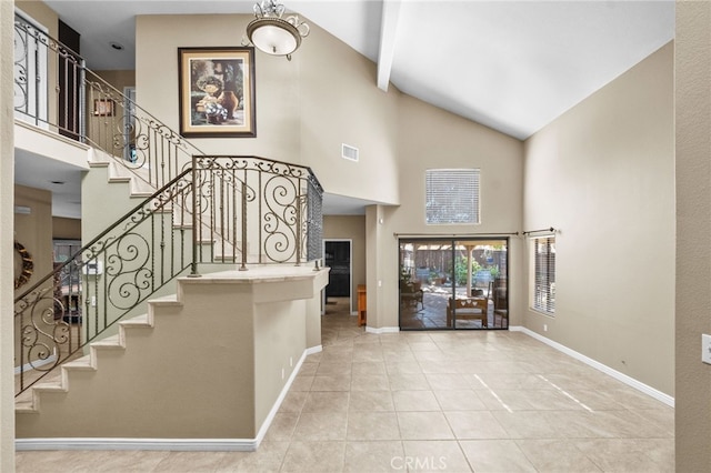 foyer featuring baseboards, visible vents, tile patterned flooring, stairs, and high vaulted ceiling