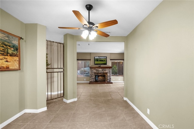 interior space featuring tile patterned flooring, a fireplace, baseboards, and ceiling fan