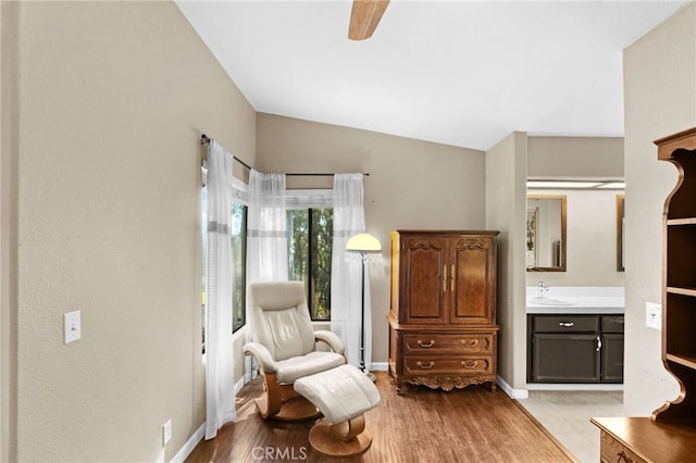 sitting room with light wood-type flooring, lofted ceiling, and baseboards