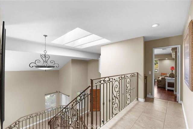 hall featuring tile patterned flooring, recessed lighting, a skylight, an upstairs landing, and baseboards