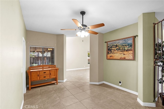 empty room with ceiling fan, baseboards, and light tile patterned flooring