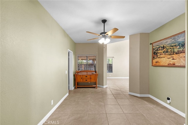 empty room featuring light tile patterned floors, ceiling fan, and baseboards