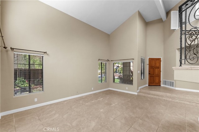 tiled empty room featuring high vaulted ceiling, visible vents, and baseboards