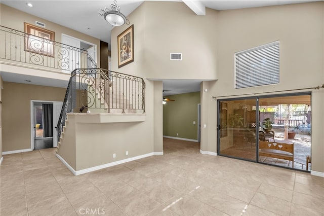 interior space featuring baseboards, visible vents, a ceiling fan, stairs, and high vaulted ceiling