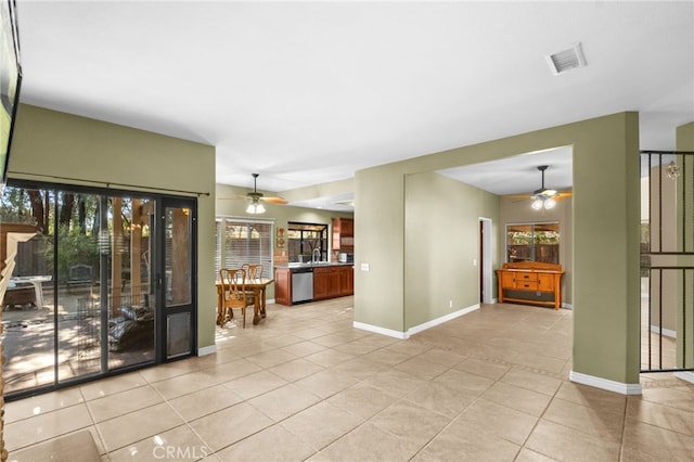 empty room featuring light tile patterned floors, baseboards, visible vents, and a ceiling fan