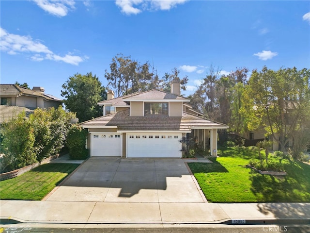 traditional home featuring driveway, a garage, a chimney, a tiled roof, and a front lawn