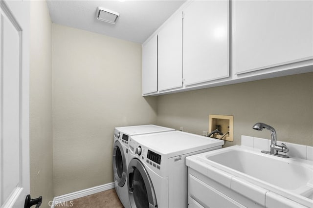 washroom featuring washing machine and dryer, a sink, cabinet space, and baseboards