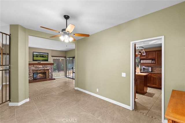 interior space featuring a toaster, a fireplace, light tile patterned floors, ceiling fan, and baseboards