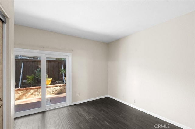 spare room featuring dark wood-style flooring and baseboards