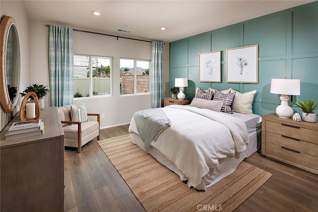 bedroom featuring recessed lighting, visible vents, dark wood finished floors, and a decorative wall