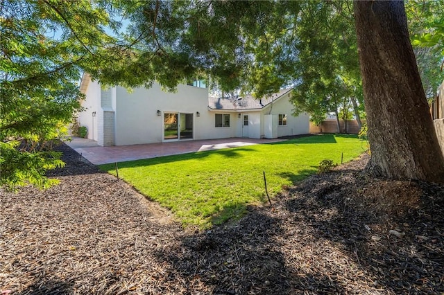 back of house with stucco siding, a patio area, a yard, and fence