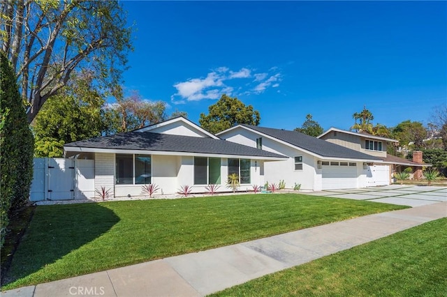 view of front of property with driveway, an attached garage, a gate, and a front lawn