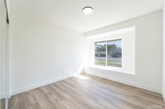 spare room featuring baseboards and light wood-style floors