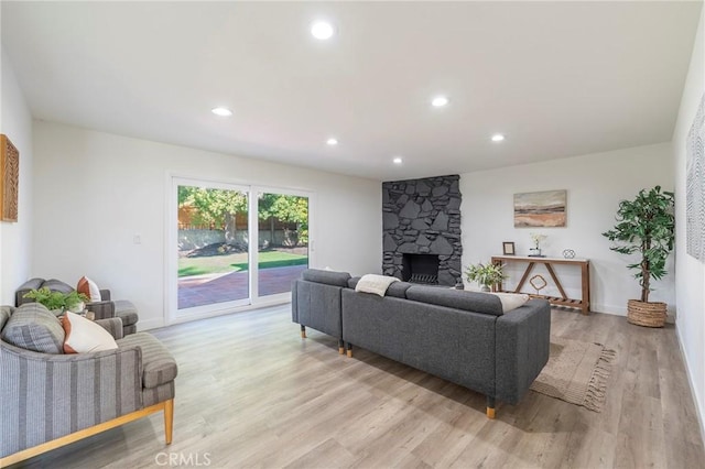 living room featuring baseboards, a fireplace, light wood-style flooring, and recessed lighting