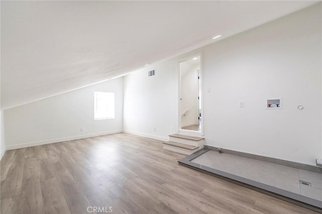 additional living space with lofted ceiling, wood finished floors, visible vents, baseboards, and stairs