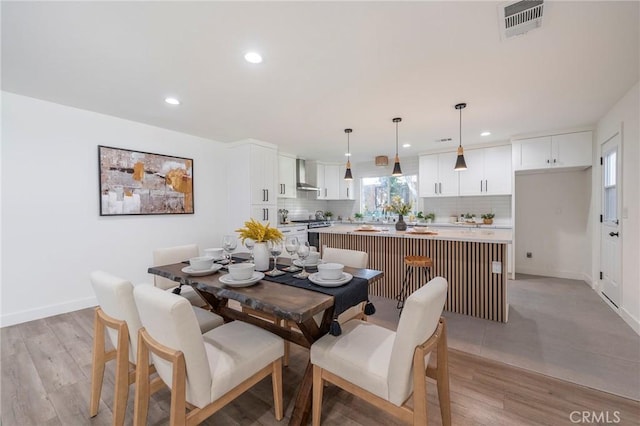 dining space with light wood-type flooring, baseboards, visible vents, and recessed lighting