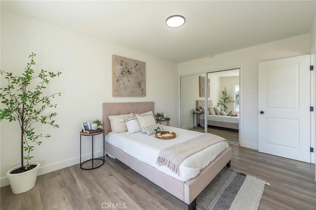 bedroom featuring a closet, wood finished floors, and baseboards