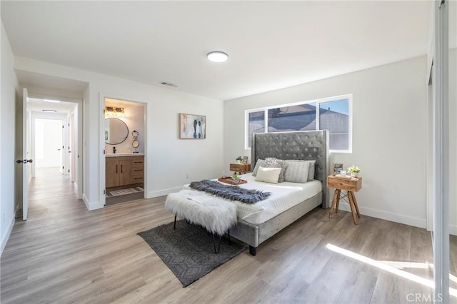 bedroom featuring ensuite bath, light wood-style floors, visible vents, and baseboards