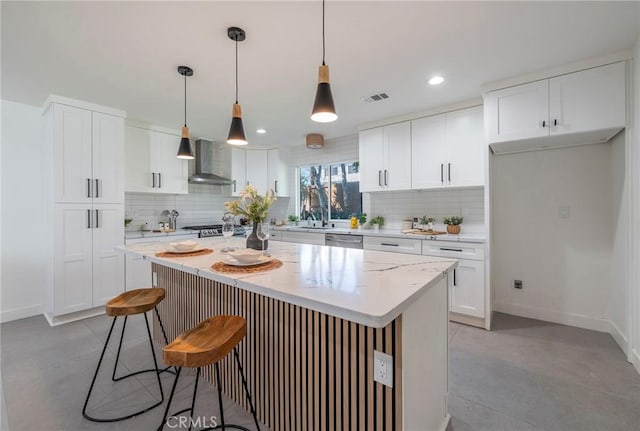 kitchen with wall chimney range hood, appliances with stainless steel finishes, visible vents, and decorative backsplash