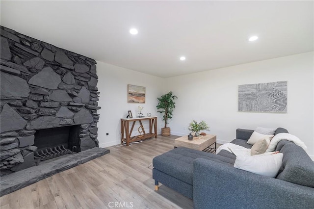 living area featuring light wood-type flooring, a fireplace, baseboards, and recessed lighting