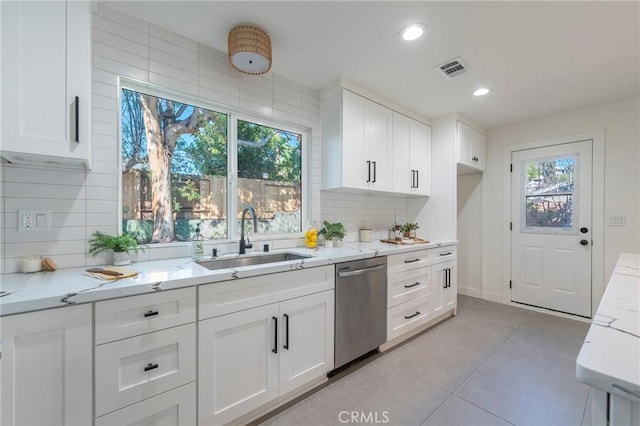 kitchen with light stone counters, white cabinetry, dishwasher, and a sink