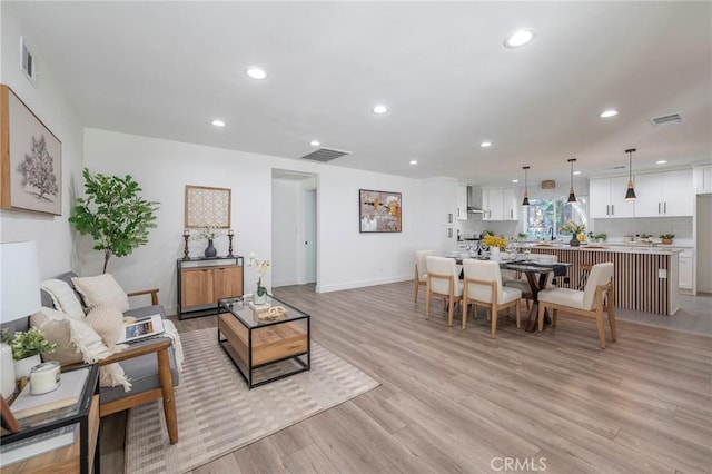 living area with recessed lighting, visible vents, and light wood-style floors