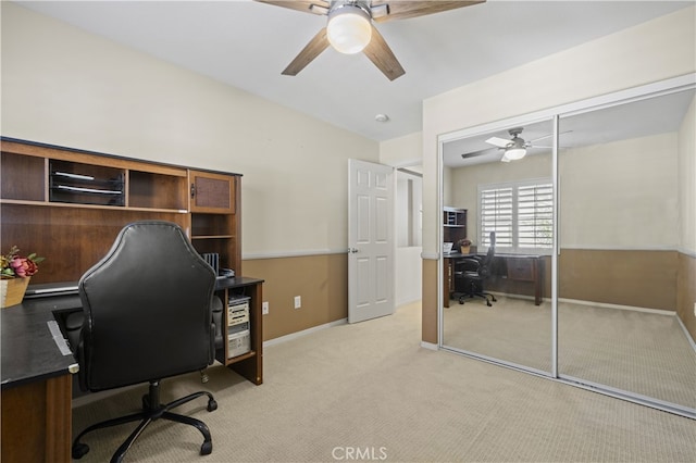 office space featuring light carpet, ceiling fan, and baseboards