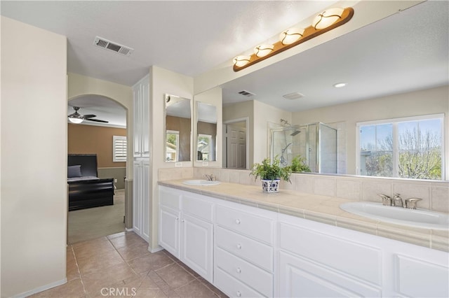 full bath with visible vents, a sink, a shower stall, and double vanity