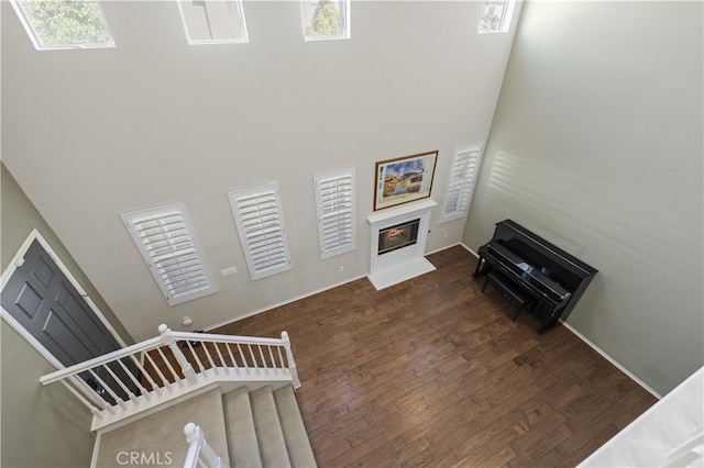 living room featuring hardwood / wood-style flooring, a high ceiling, stairway, and a glass covered fireplace