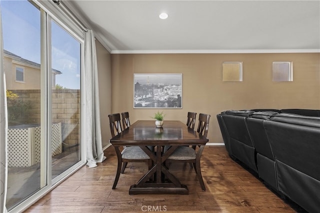 dining space with baseboards, ornamental molding, and wood finished floors