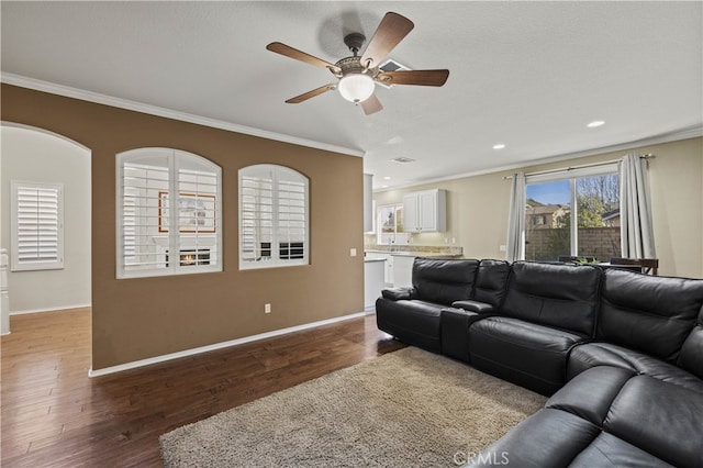 living area featuring crown molding, baseboards, and wood finished floors