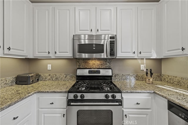 kitchen featuring stainless steel appliances, white cabinets, and light stone countertops