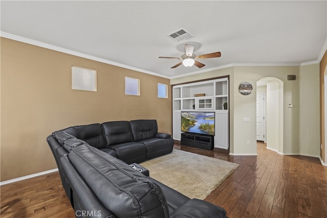 living room with arched walkways, built in shelves, dark wood-style flooring, baseboards, and crown molding