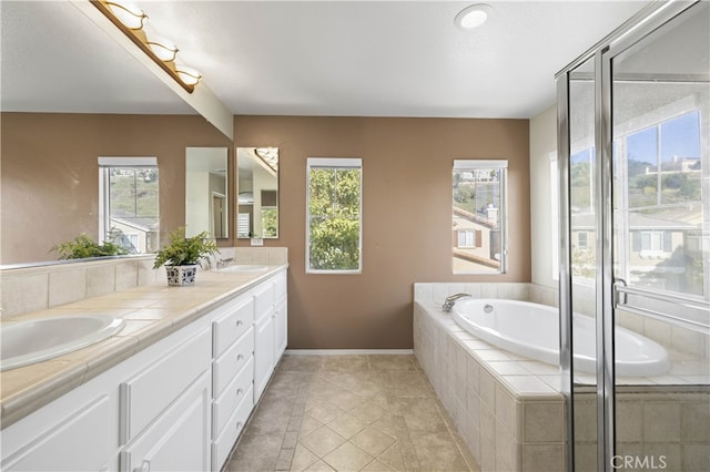 full bath with double vanity, a garden tub, baseboards, and a sink