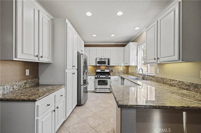 kitchen with stone countertops, white cabinets, appliances with stainless steel finishes, a peninsula, and light tile patterned flooring