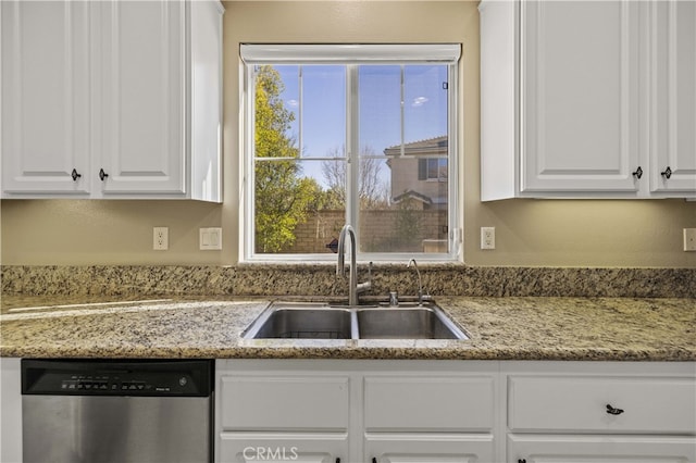 kitchen with light stone counters, white cabinets, a sink, and stainless steel dishwasher