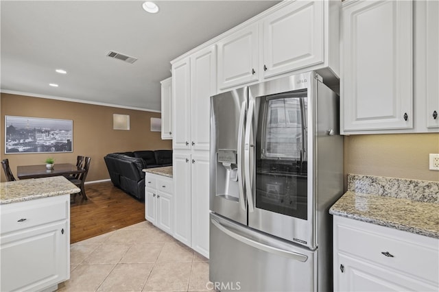 kitchen featuring white cabinets, stainless steel fridge, visible vents, and light tile patterned flooring