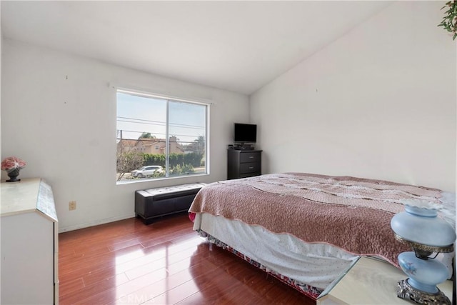 bedroom with vaulted ceiling, baseboards, and wood finished floors