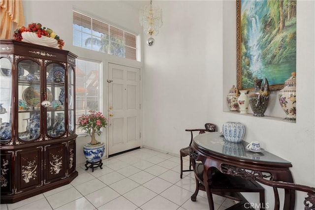 entrance foyer with a high ceiling, baseboards, a notable chandelier, and light tile patterned flooring