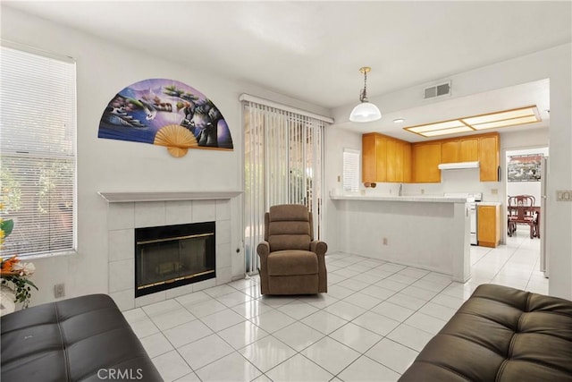 living room featuring light tile patterned floors, plenty of natural light, a fireplace, and visible vents