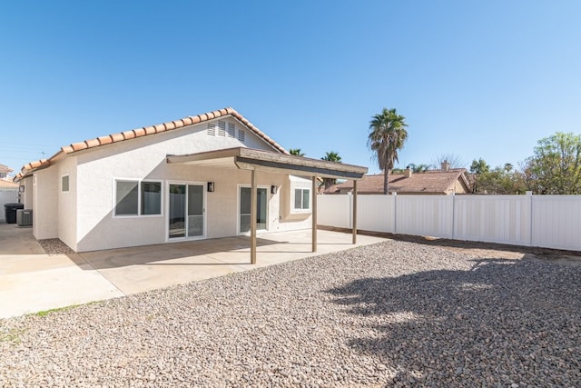 rear view of house with a patio, central AC unit, fence, and stucco siding